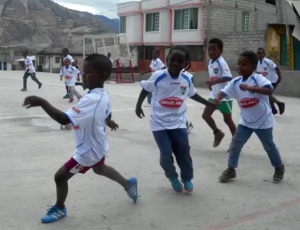 niños ecuatorianos juegan al fútbol con camisetas de la EDM